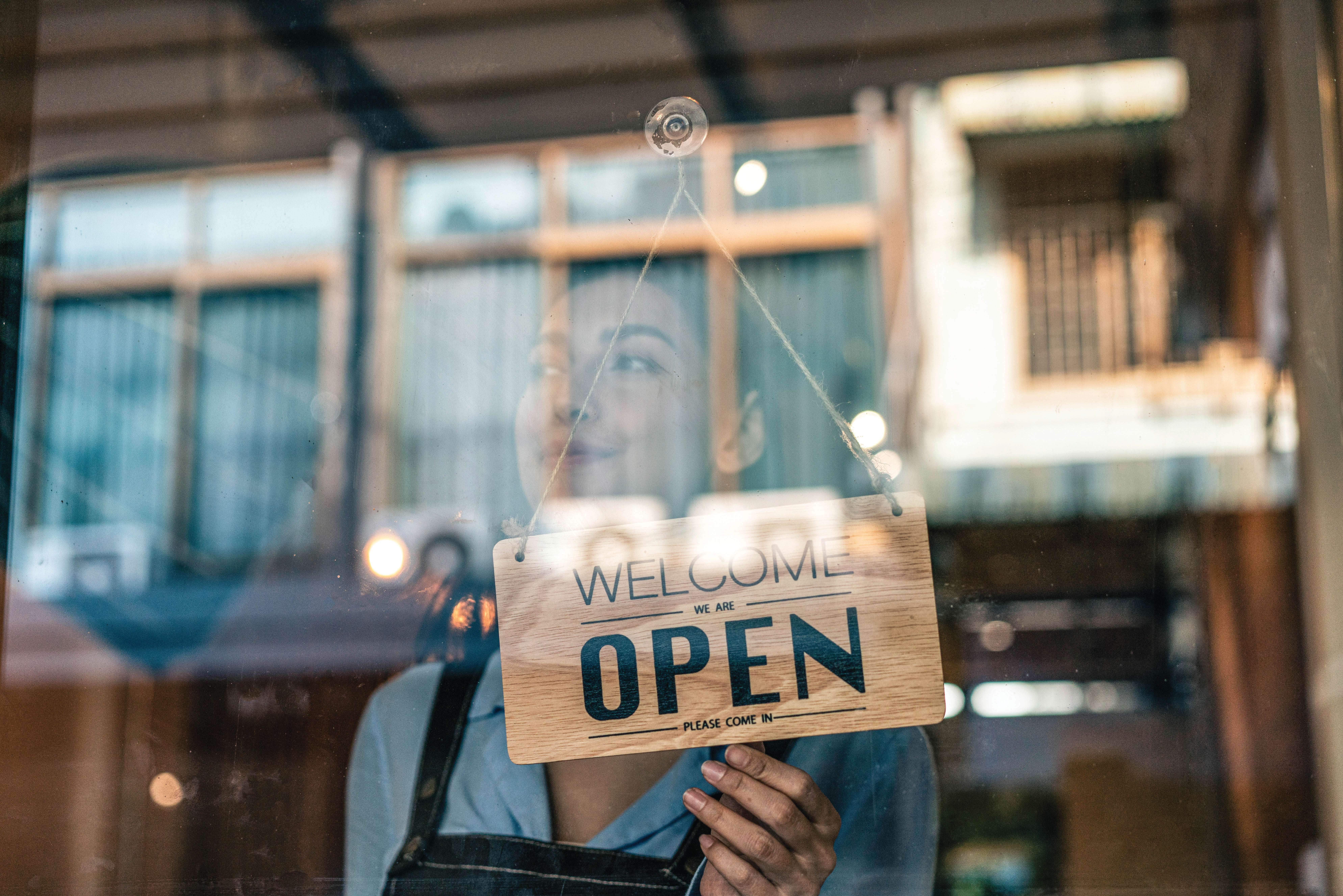 Happy business owner hanging an open sign at a cafe