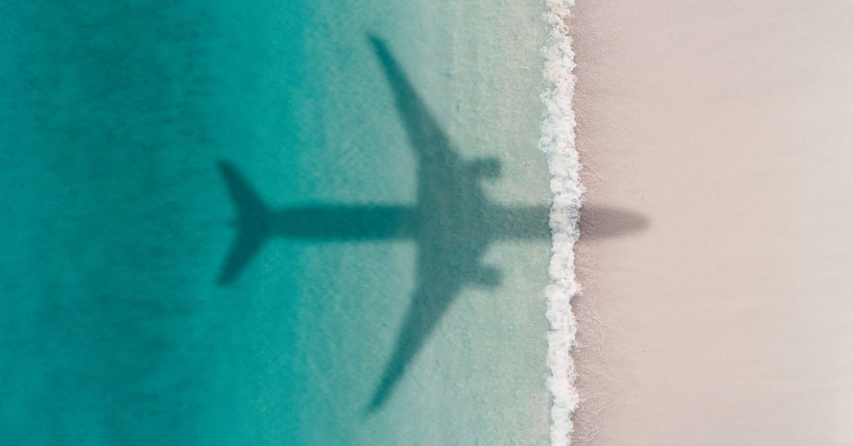 Aerial shot showing an aircraft shadow flying over an idyllic beach scene, Barbados