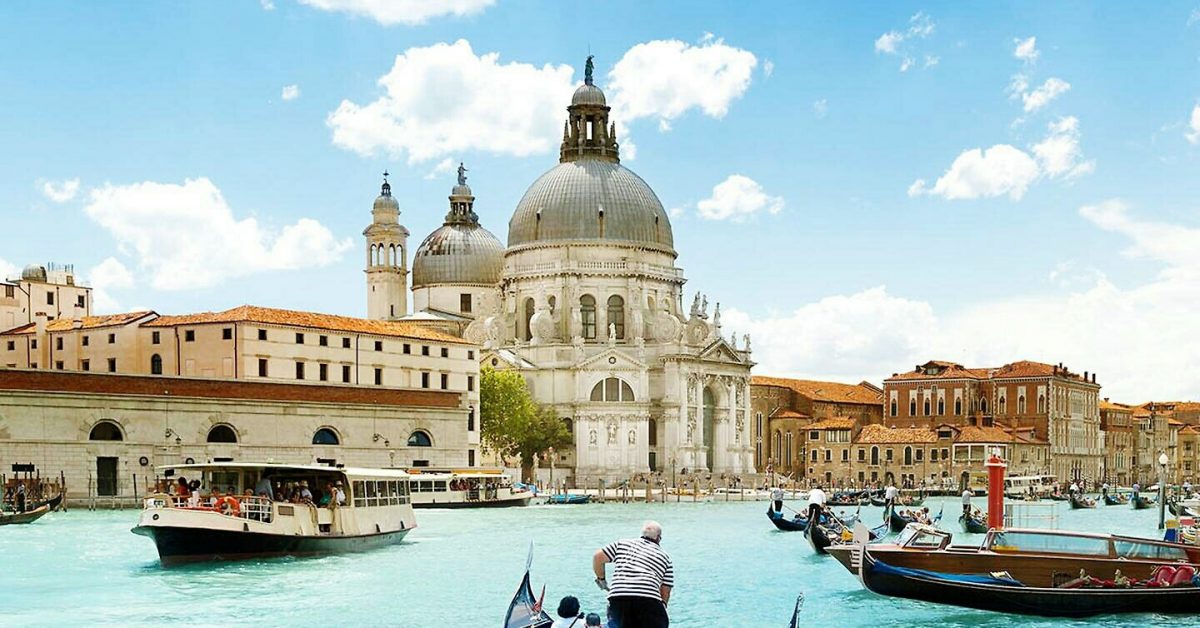 Ferry With Gondolas Sailing In Grand Canal By Santa Maria Della Salute Against Sky