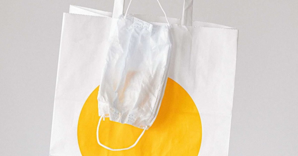 person-holding-paper-bag-and-face-mask-3987245